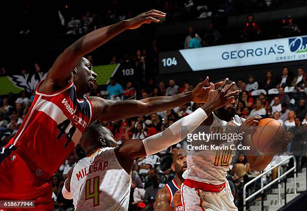 Tim Hardaway Jr. #10 of the Atlanta Hawks grabs a rebound behind Paul Millsap and Andrew Nicholson of the Washington Wizards at Philips Arena on...
