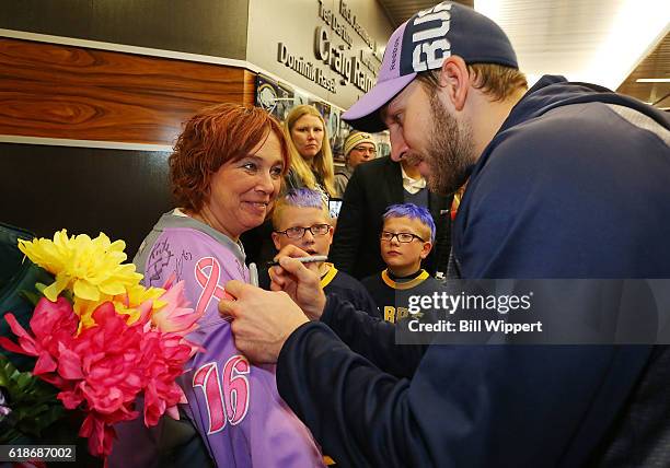 Zemgus Girgensons of the Buffalo Sabres, right, signs the jersey of Roswell Park Cancer Institute patient Colleen Williams on Hockey Fights Cancer...