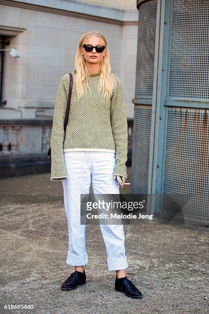 Danish model Frederikke Sofie wears green sunglasses, a green knit sweater, white jeans, and black shoes after the Giambattista Valli show at Grand...