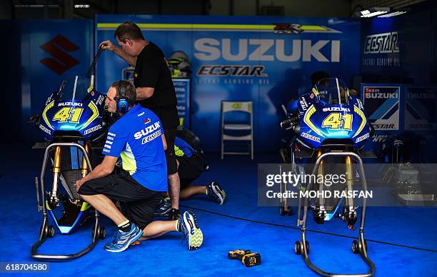 Mechanics inspect the bike of Team Suzuki Ecstar's Spanish rider Aleix Espargaro during the second practice session of the 2016 Malaysian MotoGP at...