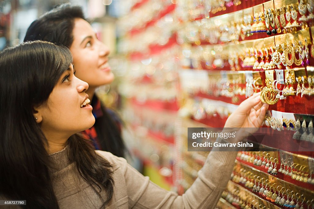 Happy girls buying earrings in jewelry shop before festival.
