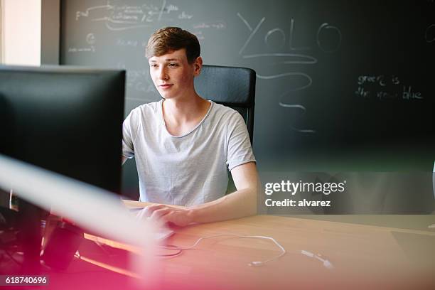 young man working at his desk - students working on pc school stock pictures, royalty-free photos & images