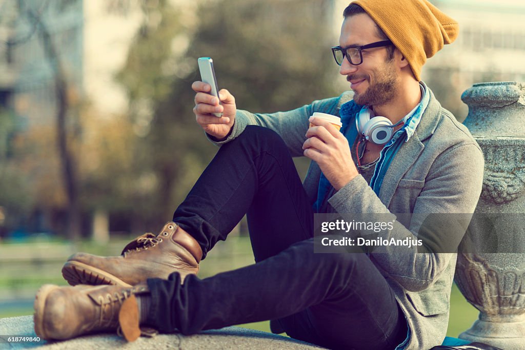 Handsome man taking a break and using his smartphone