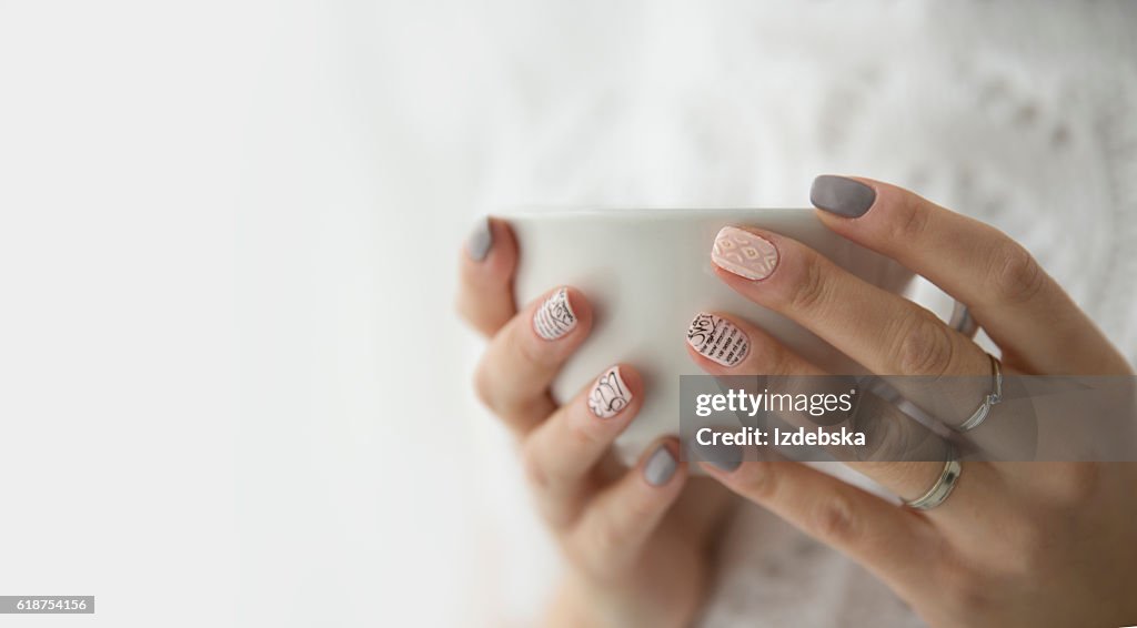 Beautiful woman's hands holding a white cup