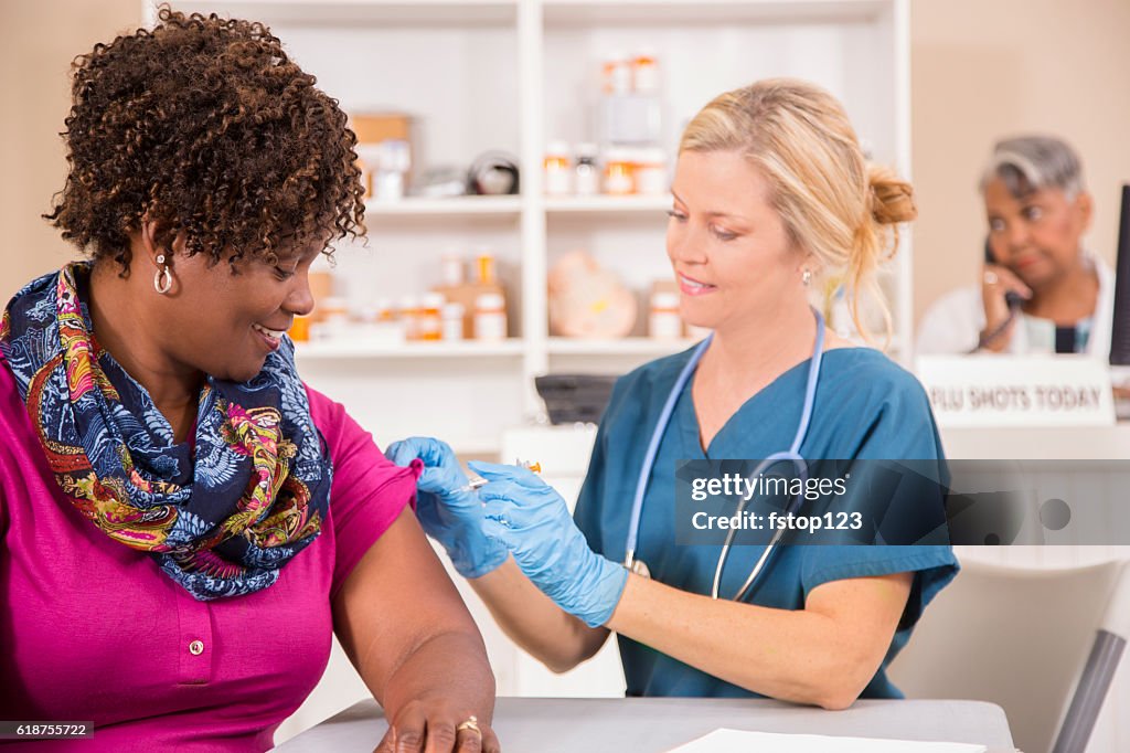 Enfermeira dá vacina contra gripe para paciente na farmácia.