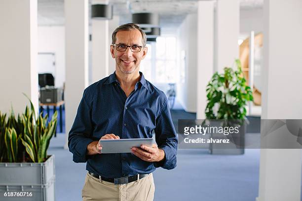 successful senior businessman standing in office - directeur stockfoto's en -beelden