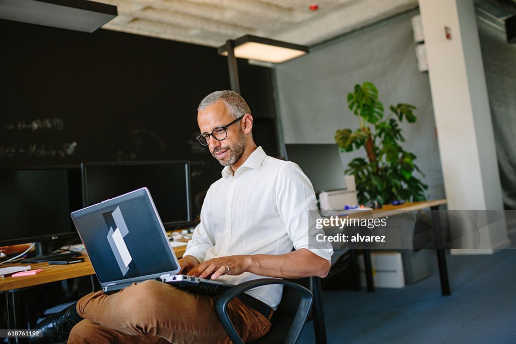 Mature businessman using laptop at startup
