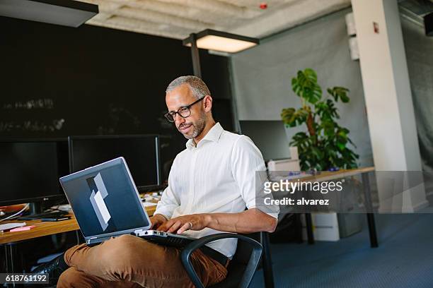 mature businessman using laptop at startup - founder stock pictures, royalty-free photos & images