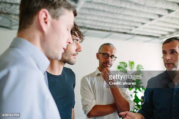 businesspeople having a standing meeting in office - four people stock pictures, royalty-free photos & images