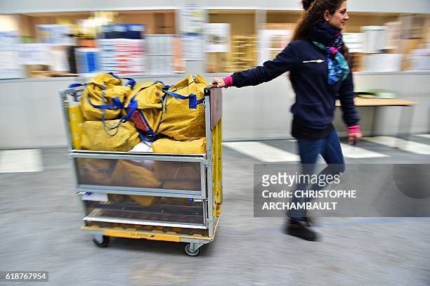 Postwoman Celia Ruivo-Alves pulls a trolley of bags containing mails during her morning round in Chevilly-Larue, southern Paris, on October 20, 2016....