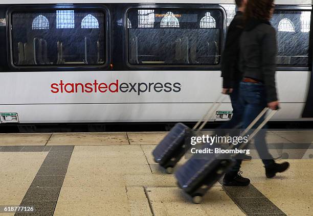 Passengers pull luggage past a Stansted Express train service, serving London Stansted Airport, operated by Manchester Airports Group , at Liverpool...