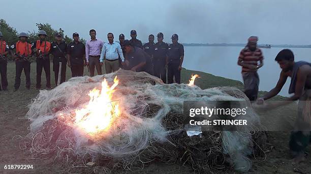 In this photograph taken on October 27 Bangladeshi law enforcers light an illegal mesh net that is used to catch Hilsa fish in the southern river...
