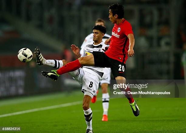 Mahmoud Dahoud of Gladbach and Makoto Hasebe of Frankfurt battle for the ball during the Bundesliga match between Borussia Moenchengladbach and...