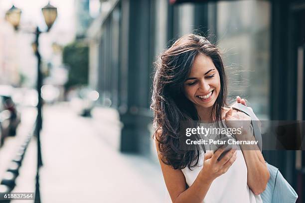 beautiful woman texting on the street - window shopping stock pictures, royalty-free photos & images