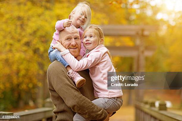 single father and daughters posing together in autumnal park surroundings - widower stock pictures, royalty-free photos & images