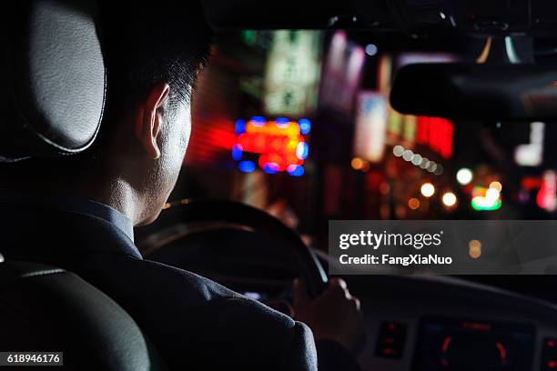 view of businessman driving car at night - limo night stock pictures, royalty-free photos & images