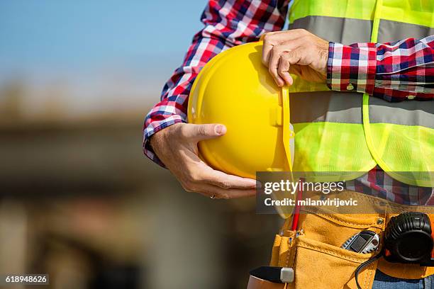 young construction worker holding a yellow helmet - health and safety stock pictures, royalty-free photos & images