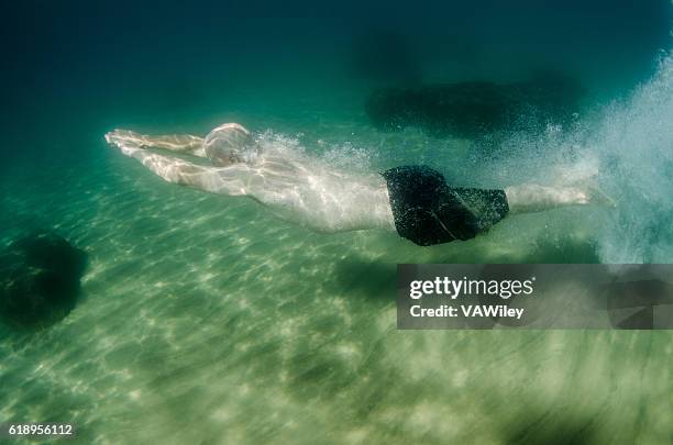 man swimming underwater in lake tahoe - midlife crisis stock pictures, royalty-free photos & images