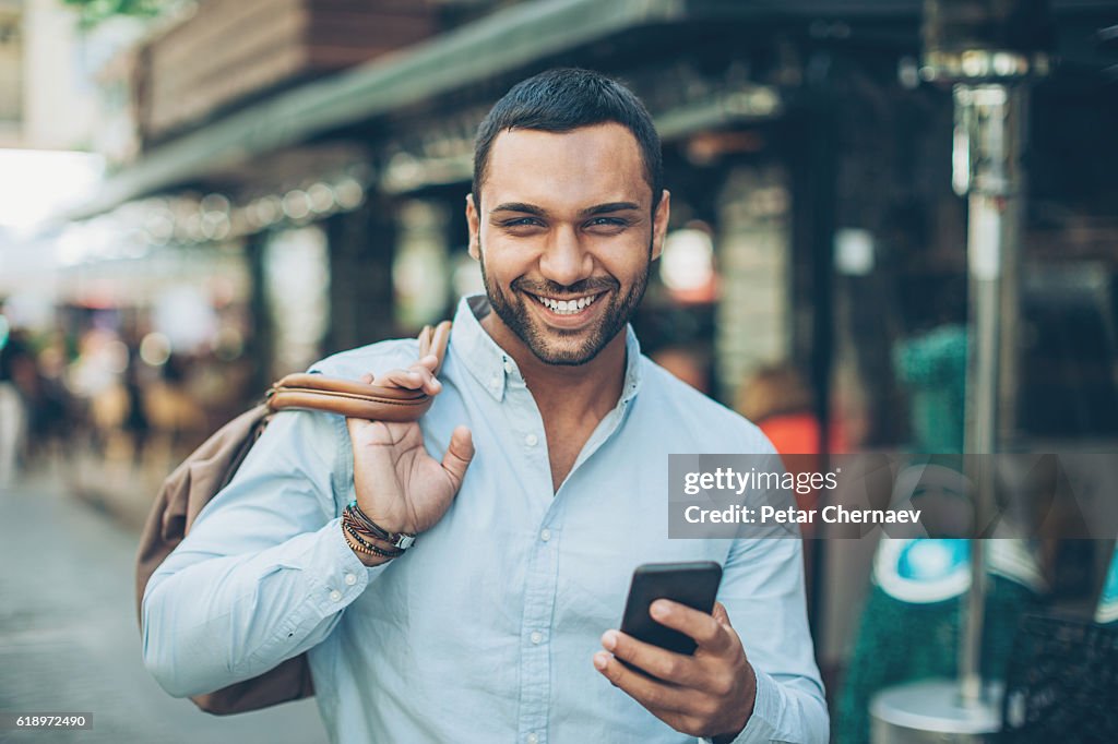 Hombre sonriente con teléfono en la calle