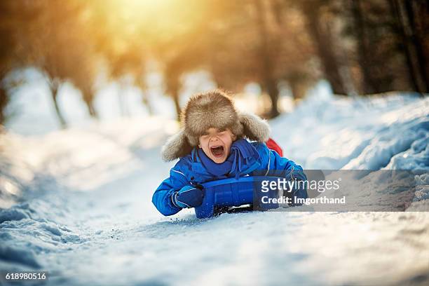 kleiner junge mit extremen spaß auf seinem schlitten - wintersport stock-fotos und bilder