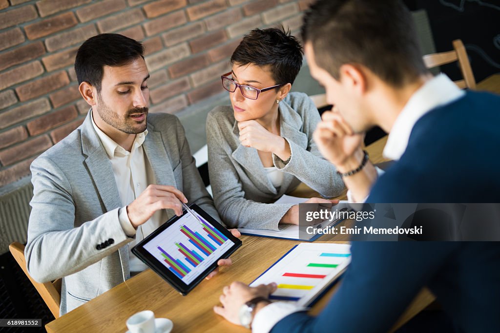 Geschäftsleute diskutieren Marktforschungsstatistiken während eines Business Meetings.