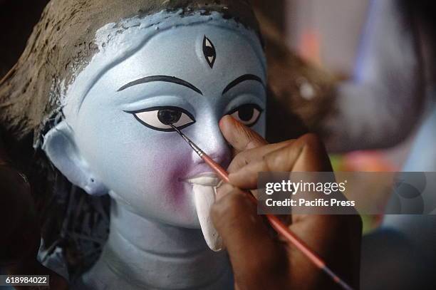 Bangladeshi artisan gives final touch to the clay idol of Hindu Goddess Kali at Shakhari Bazaar. Kali Puja also known as Shyama Puja or Mahanisha...