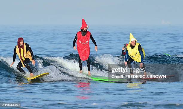 Ketchup rides between a Hot Dog and Mustard as surfers in costume ride waves at Blackie's 10th annual Halloween Surf contest in Newport Beach,...