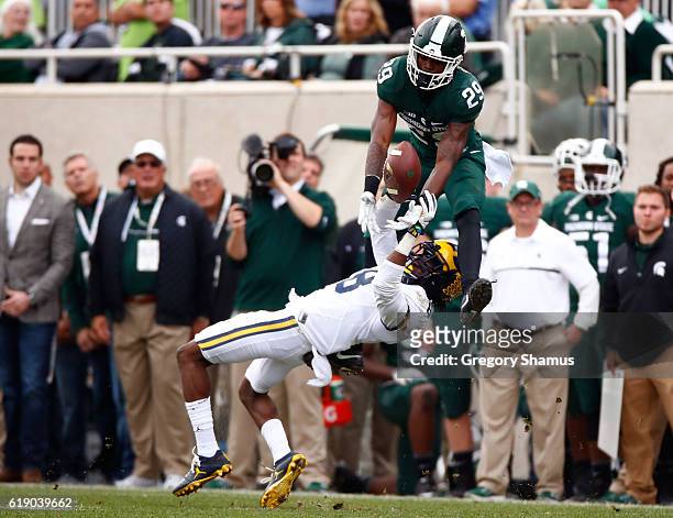 Malik Smith of the Michigan State Spartans tries to pull down a fourth quarter catch over Channing Stribling of the Michigan Wolverines at Spartan...