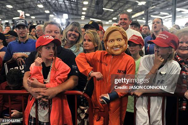 Child dressed in a mock Hillary Clinton mask and prison suit listens as Republican Presidential nominee Donald Trump addresses a capacity crowd at...