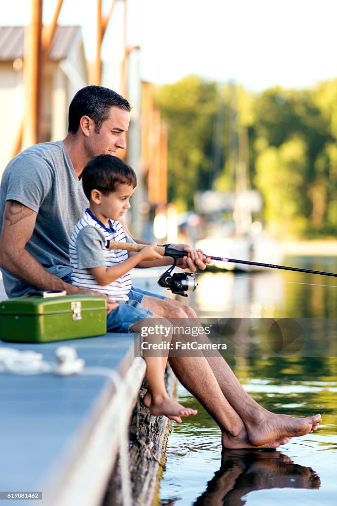 Father teaching his son how to hold a fishing rod
