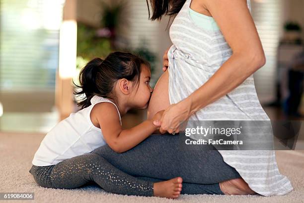 cute young ethnic girl kissing mommys pregnant belly - belly kissing stock pictures, royalty-free photos & images