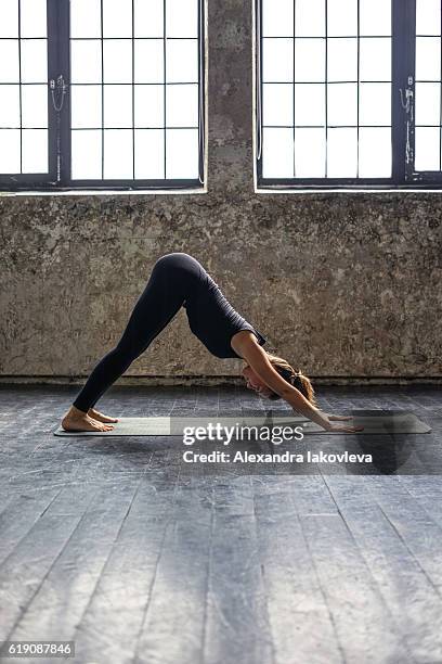 young woman practicing yoga in urban loft: downward facing dog - downward facing dog position stock pictures, royalty-free photos & images