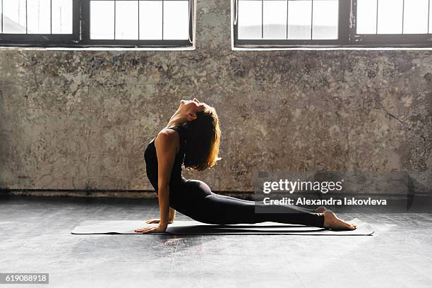 young woman practicing yoga in urban loft: upward facing dog - upward facing dog position stock pictures, royalty-free photos & images