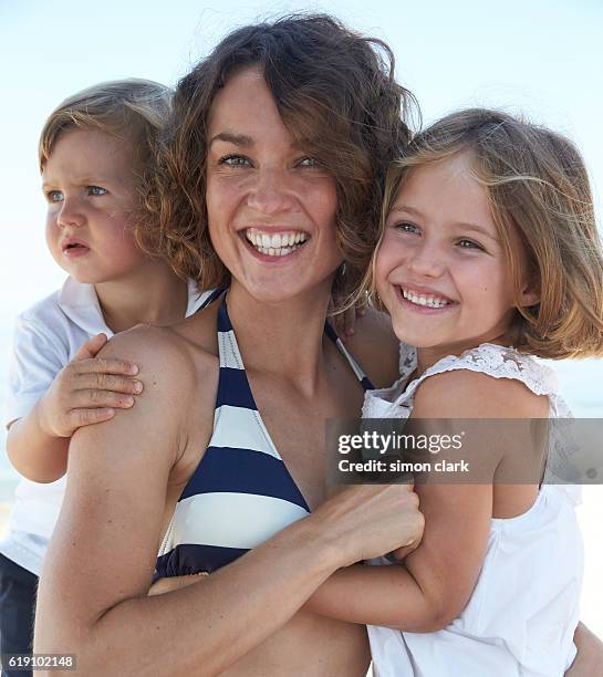 mother son and daughter embrace on beach - bambina bionda occhi verdi foto e immagini stock