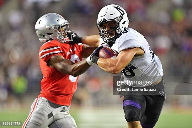 Austin Carr of the Northwestern Wildcats fends off Damon Arnette of the Ohio State Buckeyes while picking up 27-yards in the fourth quarter at Ohio...