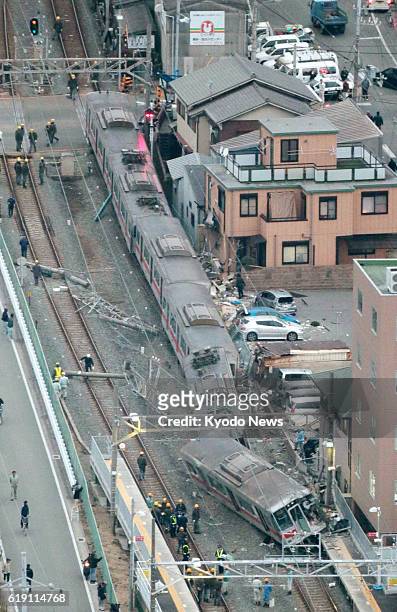 Japan - Photo from a Kyodo News helicopter shows a train operated by Sanyo Electric Railway Co. That derailed after colliding with a flatbed carrier...