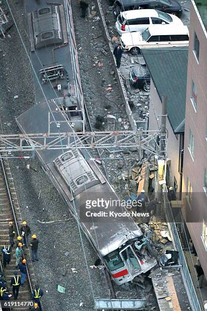 Japan - Photo from a Kyodo News helicopter shows a train operated by Sanyo Electric Railway Co. That derailed after colliding with a flatbed carrier...