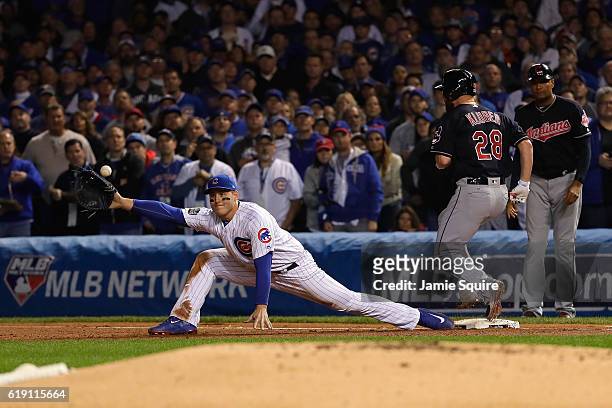 Anthony Rizzo of the Chicago Cubs attempts to catch a throw from Kris Bryant as Corey Kluber of the Cleveland Indians reaches first base for a single...