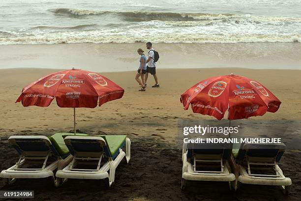 In this photograph taken on September 25 foreign tourists walk past a row of empty beach chairs outside a shack on Anjuna Beach in Goa. Goa has long...