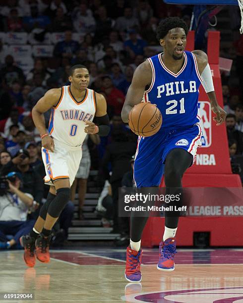 Joel Embiid of the Philadelphia 76ers dribbles the ball up the court past Russell Westbrook of the Oklahoma City Thunder at Wells Fargo Center on...