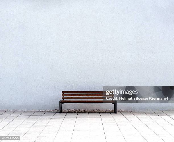 empty bench in front of a white wall - zitbank stockfoto's en -beelden