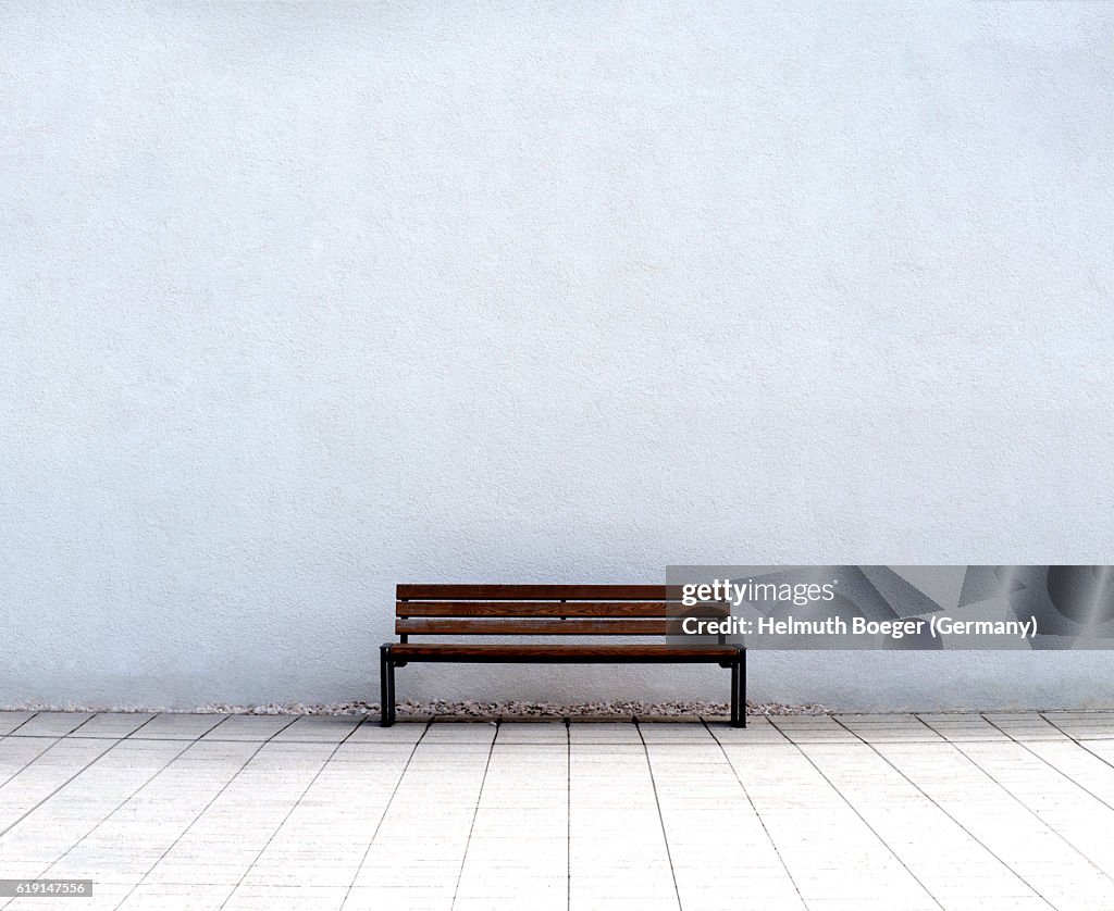 Empty Bench in front of a white wall
