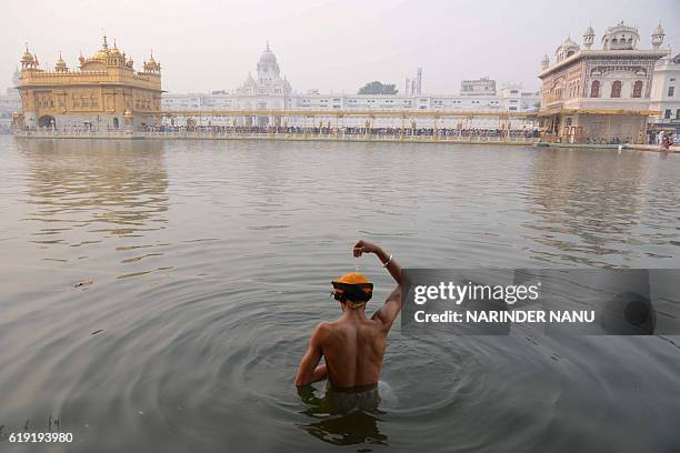 An Indian Sikh devotee bathes in the holy sarovar on the occasion of Bandi Chhor Divas, or Diwali, at the Golden Temple in Amritsar on October 30,...