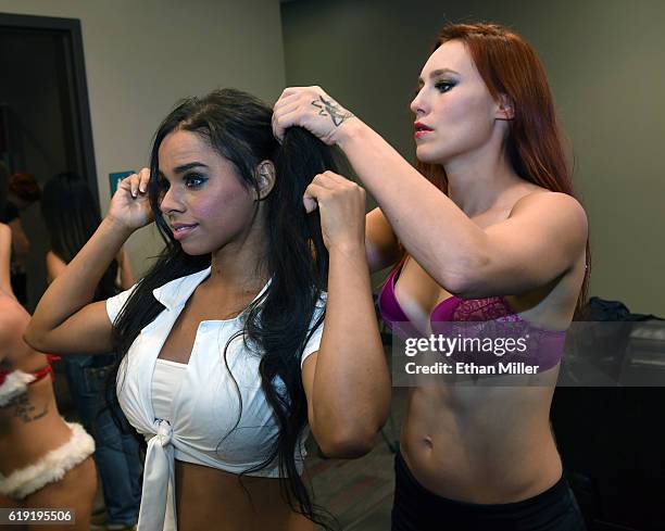 Fighter Jolene "The Valkyrie" Hexx helps fighter Roxy "Roundhouse" Michaels with her hair backstage as they get ready to compete during "Lingerie...