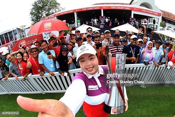 Shanshan Feng of China imitates a selfie as she poses with the Sime Darby LPGA trophy in front of cheering fans after she won it 17 under par 267...