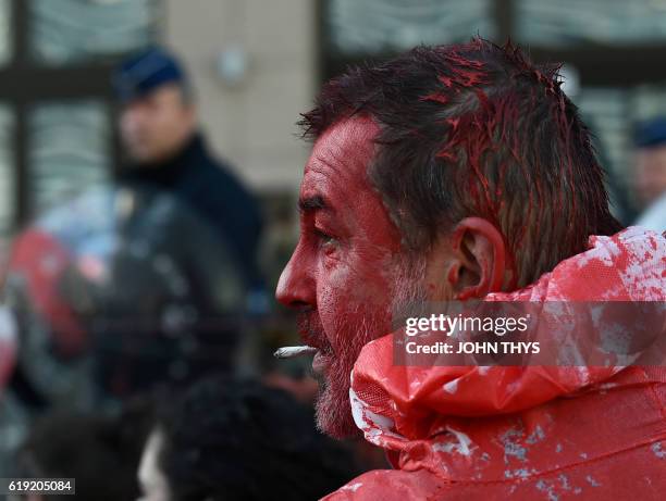 Protestors wearing protective suits covered in fake-blood gather before a police barricade before the start of the EU-Canada summit to conclude the...