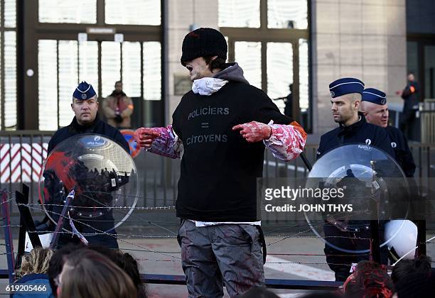 Protestor wearing a protective suit covered in fake-blood gestures before a police barricade before the start of the EU-Canada summit to conclude the...