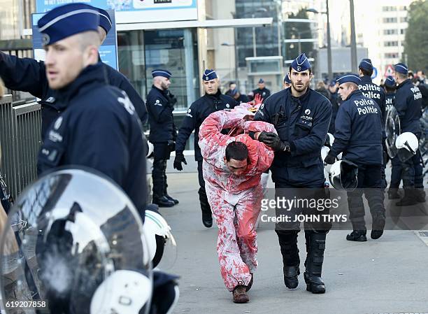 Police arrest a protestor wearing a protective suit covered in fake-blood before the start of the EU-Canada summit to conclude the Comprehensive...