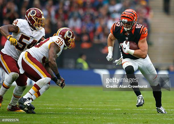 Tyler Eifert of the Cincinnati Bengals rushes the ball against Donte Whitner Sr. #39 and Mason Foster of the Washington Redskins during the NFL...