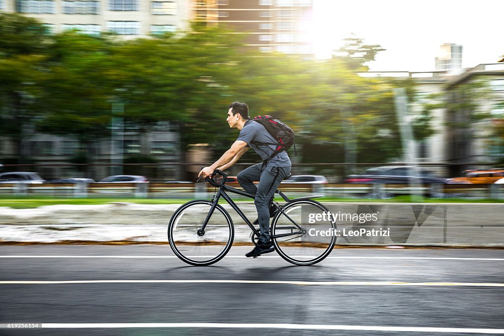 Joven en bicicleta en la ciudad, viajando al trabajo